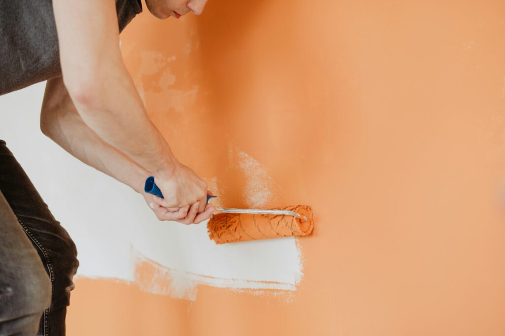 painting brush with bright orange paint for wall renovation, home improvement, house paint, new